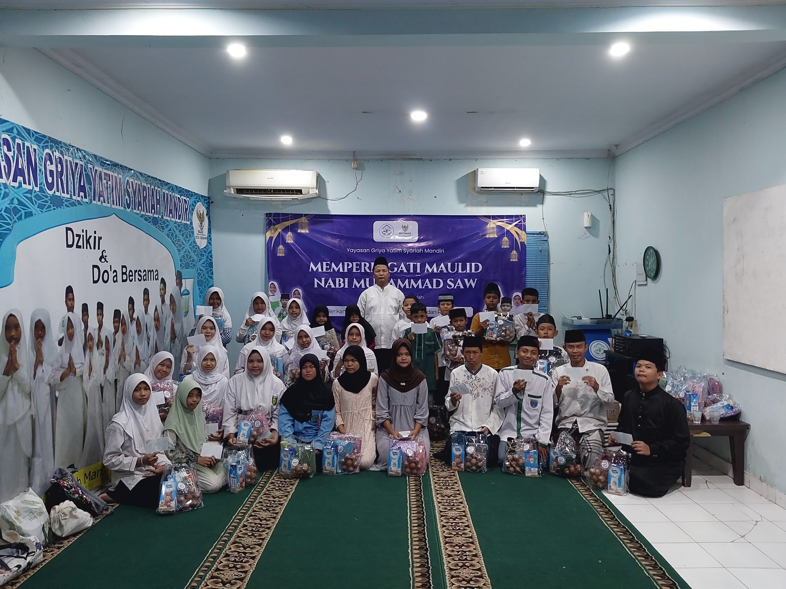 Anak-anak yatim dan dhuafa penerima santunan Maulid Nabi GYS tersenyum bahagia sambil memegang bingkisan gizi, alat sholat, dan uang tunai.